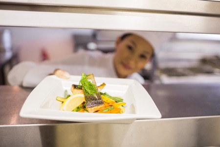 Closeup of a female chef with cooked food in the kitchenの写真素材
