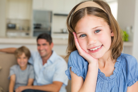Portrait of cute girl smiling with family in background at homeの写真素材