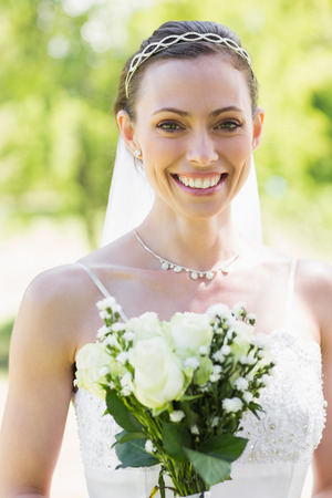Portrait of happy young bride with flowers in gardenの写真素材