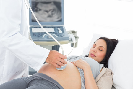 Cropped image of male doctor performing ultrasound test on pregnant woman in hospitalの写真素材