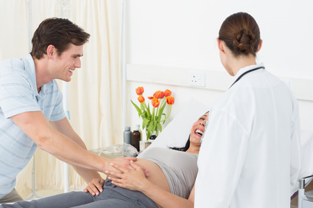 Female doctor with happy expectant couple in hospital wardの写真素材