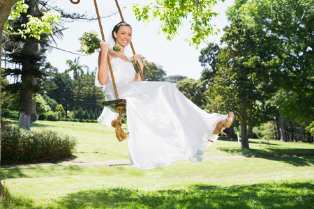 Full length portrait of young bride swinging in gardenの写真素材