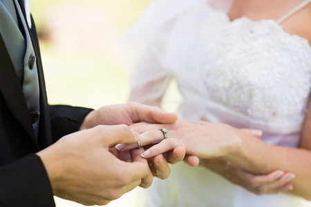 Closeup of groom placing ring on brides finger on their wedding day の写真素材