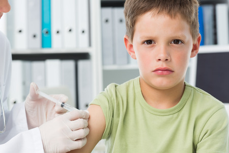 Portrait of boy receiving an injection by female pediatrician in clinicの写真素材
