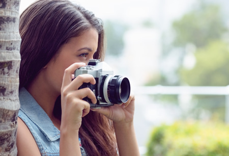 Pretty girl taking photographs outside on a sunny dayの写真素材