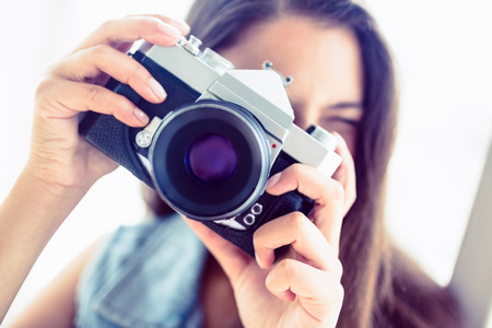 Young woman taking a photo in a bright room