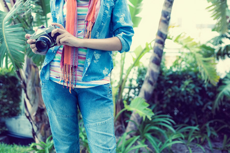 Woman wearing denim holding camera outside on a sunny day