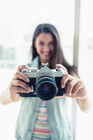 Happy young woman taking a photo at camera in a bright roomの写真素材