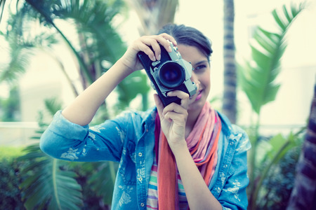 Smiling brunette taking a photo outside on a sunny day