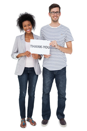 Full length portrait of a smiling couple holding a thank you note over white backgroundの写真素材