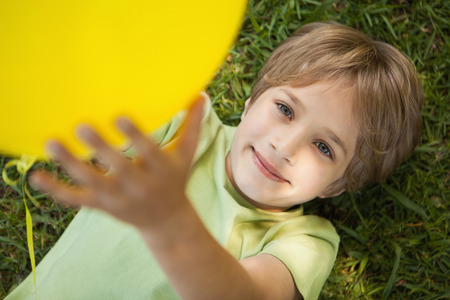 High angle view of a young boy with yellow balloon at the parkの写真素材