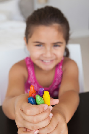 Close-up portrait of a young girl holding drawing colors at homeの写真素材