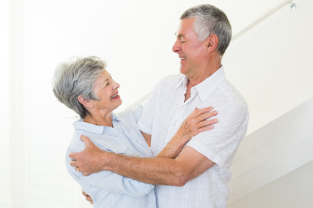 Happy senior couple dancing together at home in living roomの写真素材
