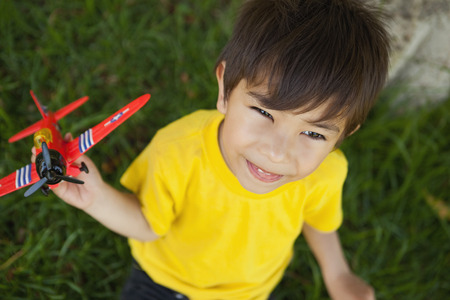 High angle view of a young boy playing with a toy plane at the parkの写真素材