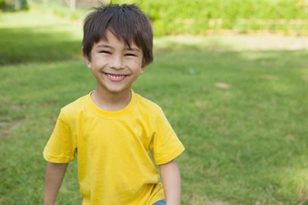 Portrait of a cheerful young boy standing at the parkの写真素材