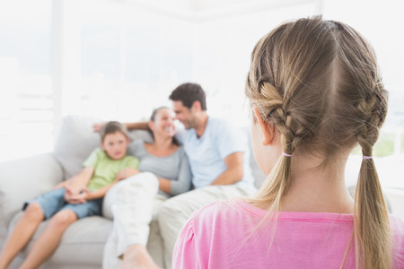 Little girl watching her family on the couch at home in the living roomの写真素材