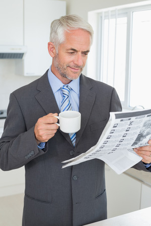 Smiling businessman having coffee in the morning before work at home in the kitchenの写真素材