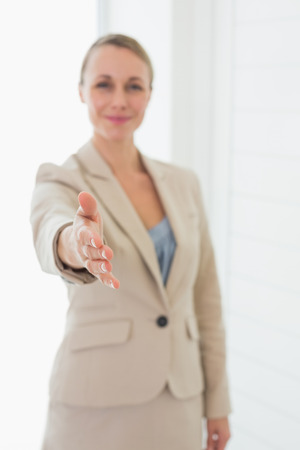 Smiling estate agent holding her hand out to camera in empty houseの写真素材