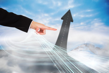 Digital composite of finger pointing to road turning into arrowの写真素材