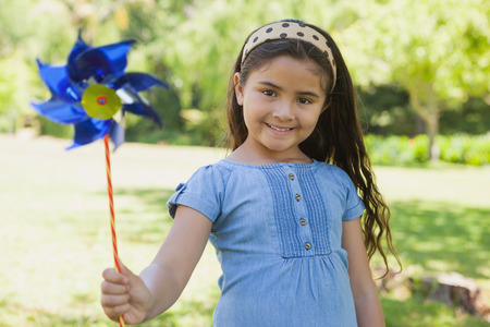 Portrait of cute little girl holding pinwheel at the park