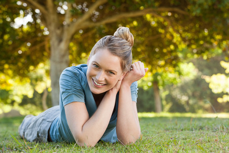 Portrait of a beautiful relaxed young woman lying on grass at the parkの写真素材