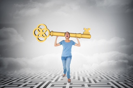 Annoyed brunette holding golden key against clouds over mazeの写真素材