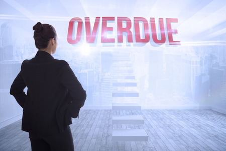 The word overdue and businesswoman with hands on hips against city scene in a roomの写真素材