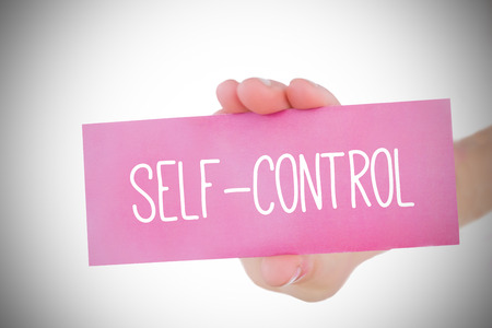 Woman holding pink card saying self control against white background with vignetteの写真素材