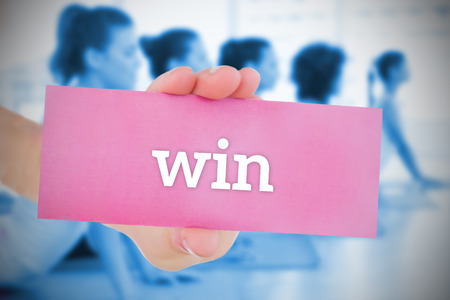 Woman holding pink card saying win against yoga class in gymの写真素材