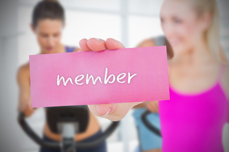 Fit blonde holding card saying member against spinning class in gymの写真素材