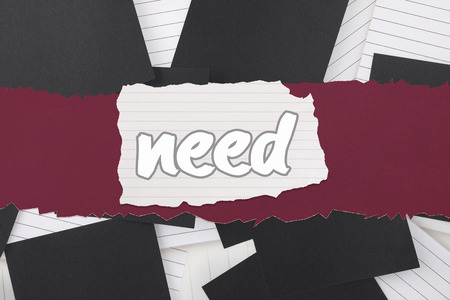 The word need against black paper strewn over notepadの写真素材
