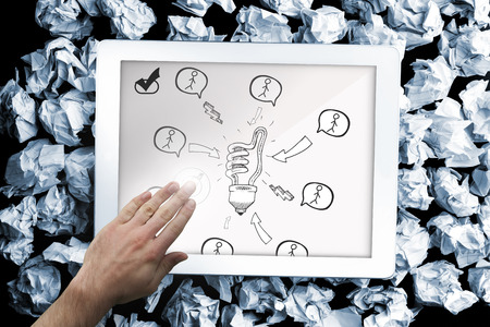 Composite image of hand touching tablet showing light bulb doodle with stick figuresの写真素材