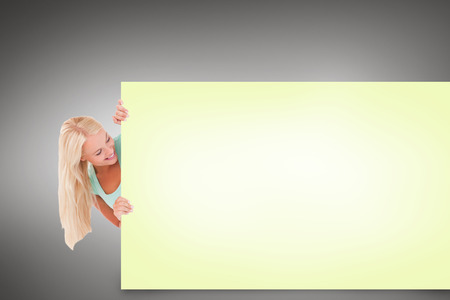 Composite image of pretty blonde showing yellow cardの写真素材