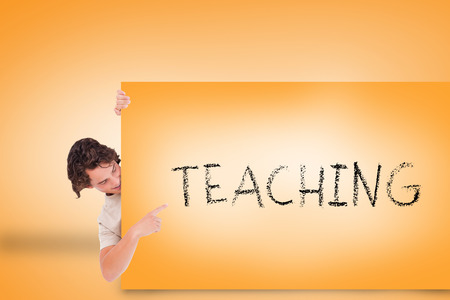 Handsome young man showing card with teaching against orange backgroundの写真素材