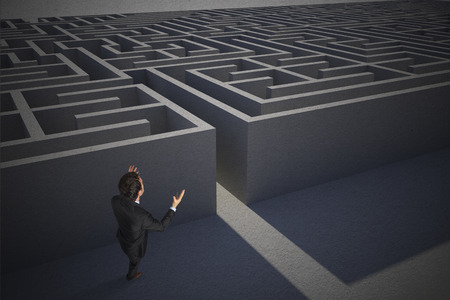 Stressed businessman gesturing against entrance to difficult maze puzzleの写真素材