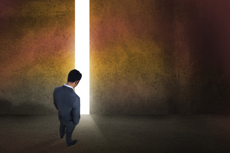 Businessman standing against door revealing bright lightの写真素材