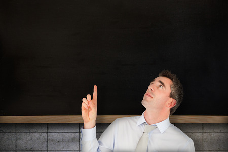 Business manager pointing against chalkboard on grey grid wallの写真素材