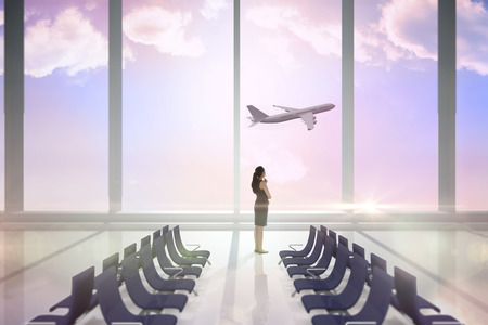 Thoughtful businesswoman against airport departure areaの写真素材