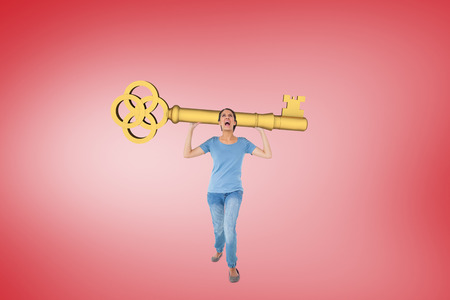 Annoyed brunette carrying large key against red vignetteの写真素材