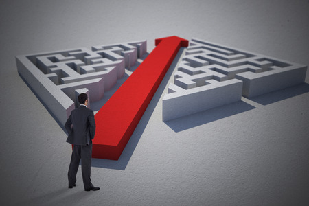 Businessman standing with hands on hips against red arrow cutting through puzzleの写真素材