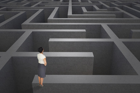 Thoughtful businesswoman against difficult maze puzzleの写真素材