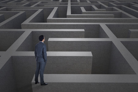 Businessman standing against difficult maze puzzleの写真素材
