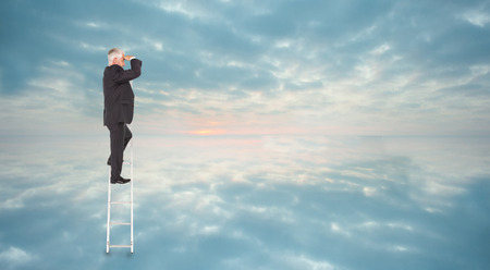 Mature businessman standing on ladder against clouds reflected on waterの写真素材