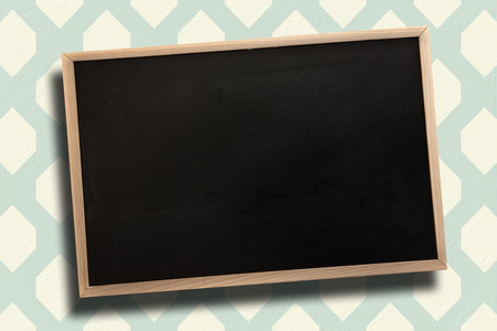 Chalkboard with wooden frame against blue and cream patterned wallpaperの写真素材