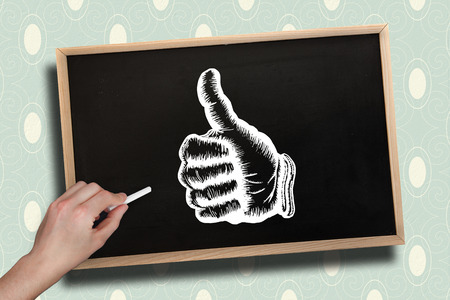 Composite image of hand drawing thumbs up with chalk on chalkboard with wooden frameの写真素材