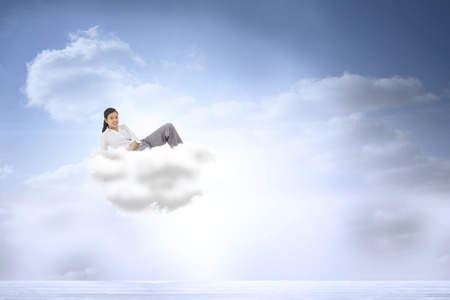 Relaxed businesswoman lying against beautiful blue sky with cloudsの写真素材