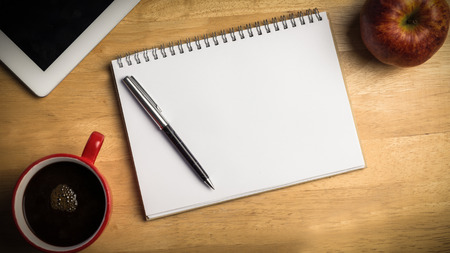 Overhead of notepad and pen on a cluttered deskの写真素材