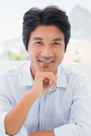 Smiling man looking at camera outside on a balconyの写真素材
