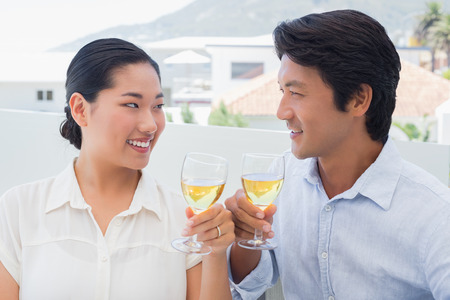 Happy couple having white wine outside on a balconyの写真素材