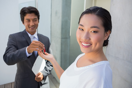 Estate agent giving house key to buyer outside a houseの写真素材